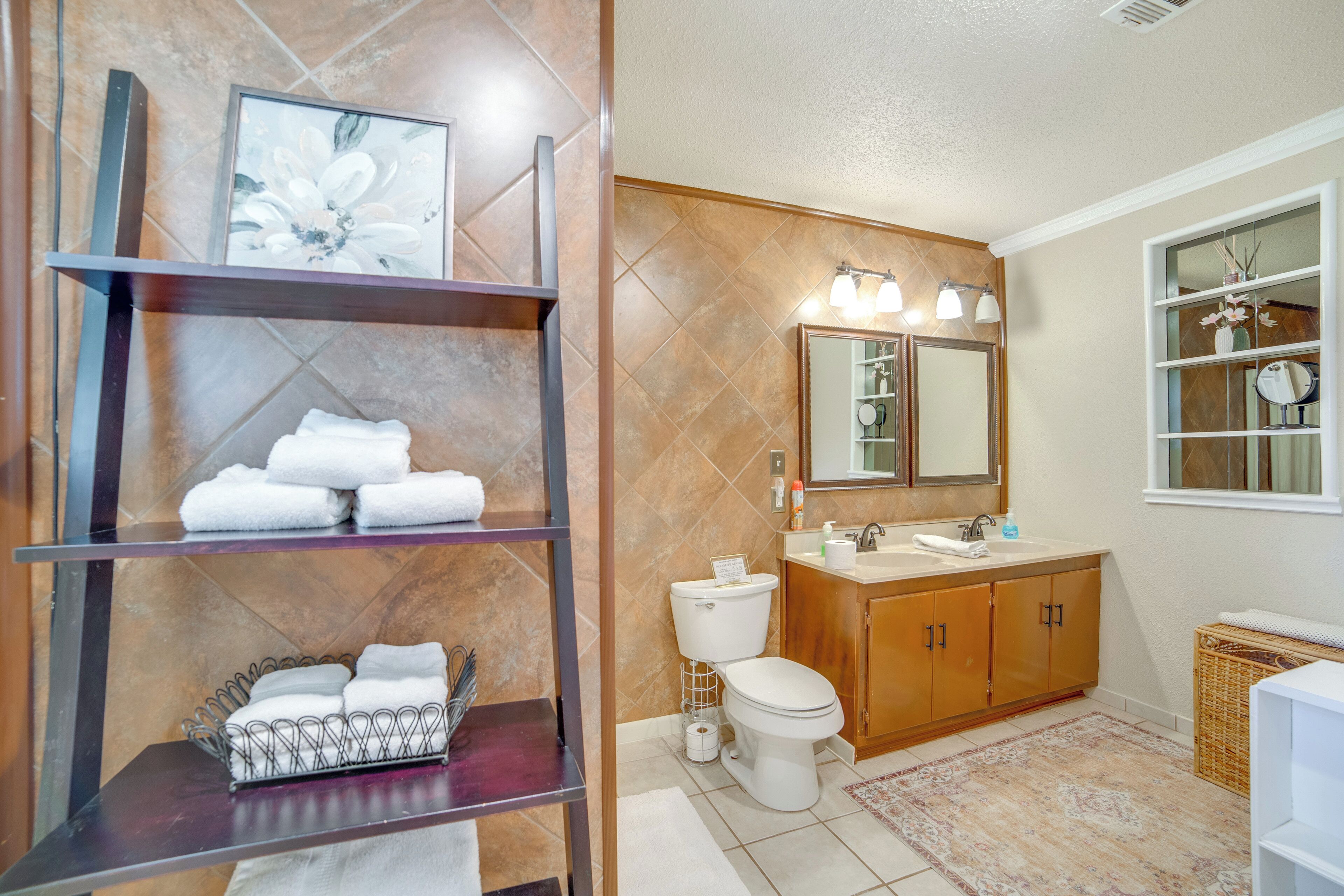 A bathroom with a toilet, sink, and shelves with towels.