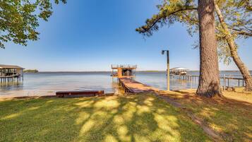 A lakeside dock with a covered seating area and a wooden walkway leading to a pier.