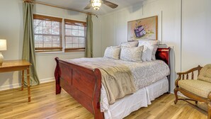 Ein Schlafzimmer mit einem hölzernen Bett, einem Holzstuhl, einem Nachttisch und einem Deckenventilator.