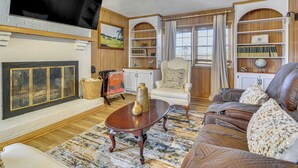 Ein Wohnzimmer mit Kamin, Fernseher, Bücherregal und einer gemütlichen Sitzecke.