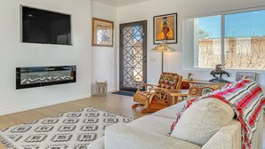 Una sala de estar con chimenea, sofá, sillón y un ventanal grande.