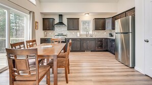 Una cocina amplia con armarios de madera oscura, un refrigerador de acero inoxidable y una mesa de comedor grande con sillas.