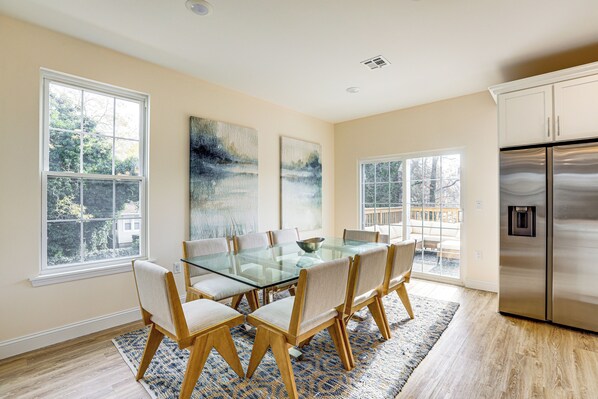 A dining area with a glass table and chairs, large windows, and a stainless steel refrigerator. - Walk to Keansburg Beach! Family Home w/ Pool (Keansburg)