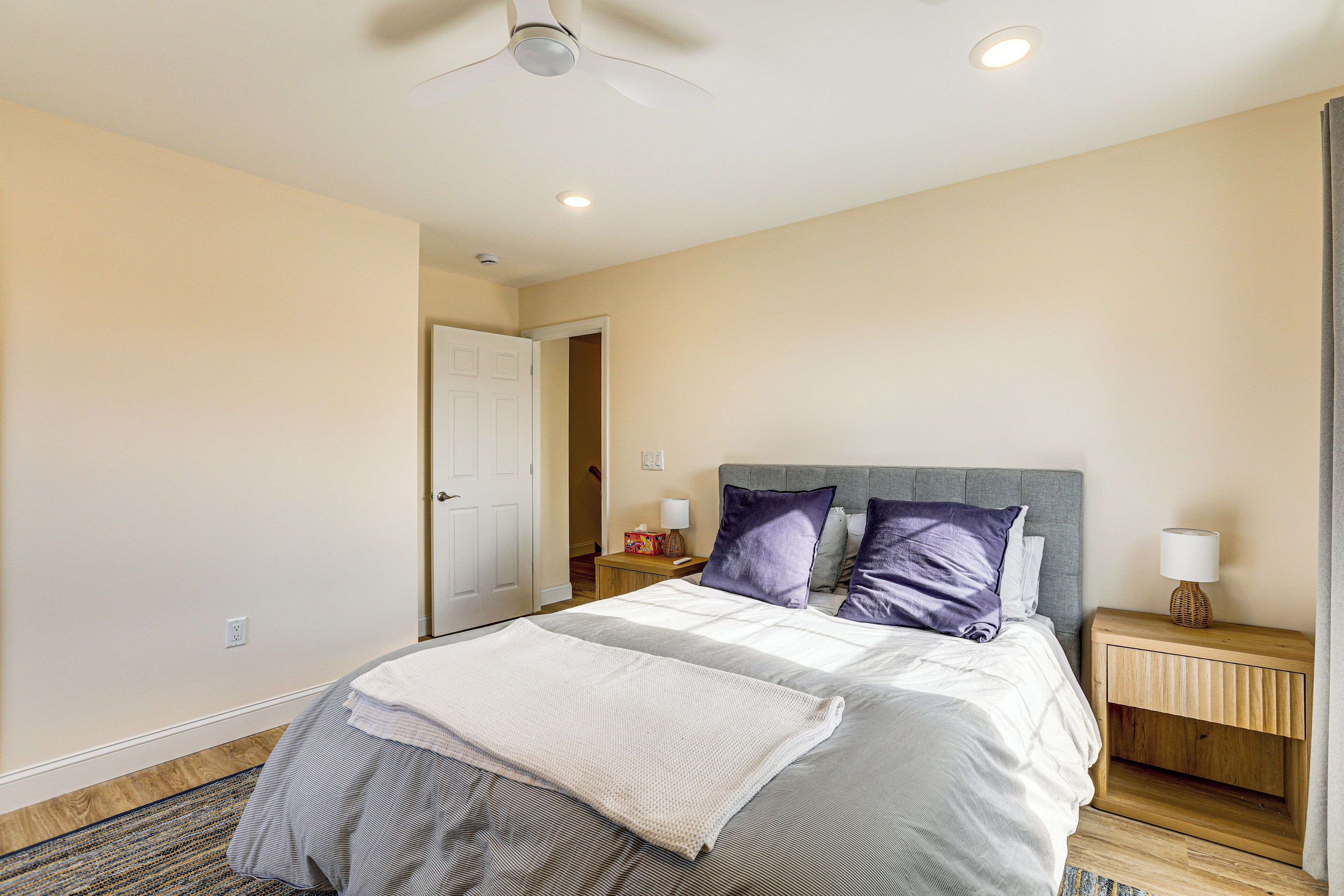 Une chambre à coucher avec un lit, une table de chevet et un ventilateur de plafond.