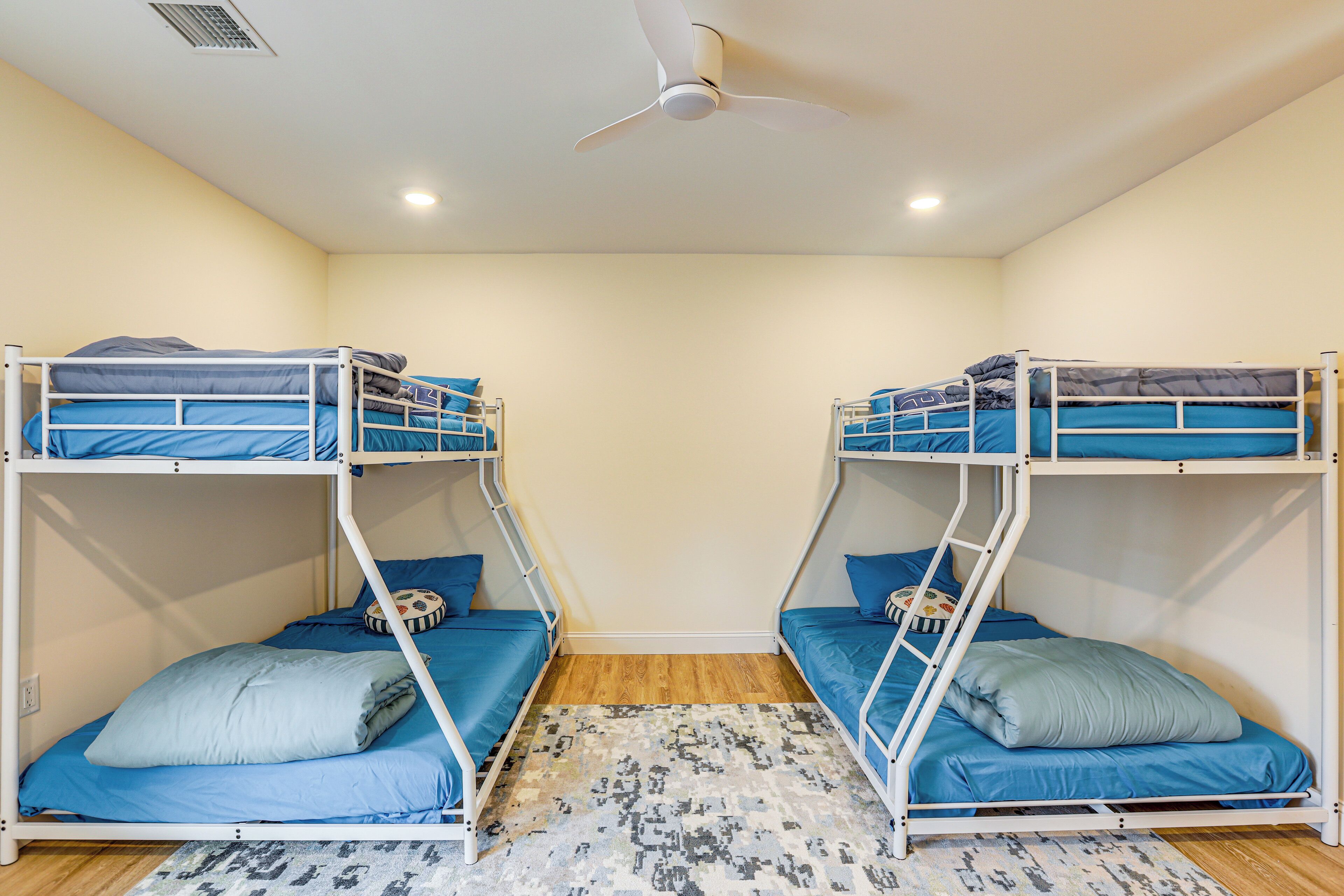 Une chambre avec deux lits superposés, un ventilateur de plafond et un tapis à motifs.