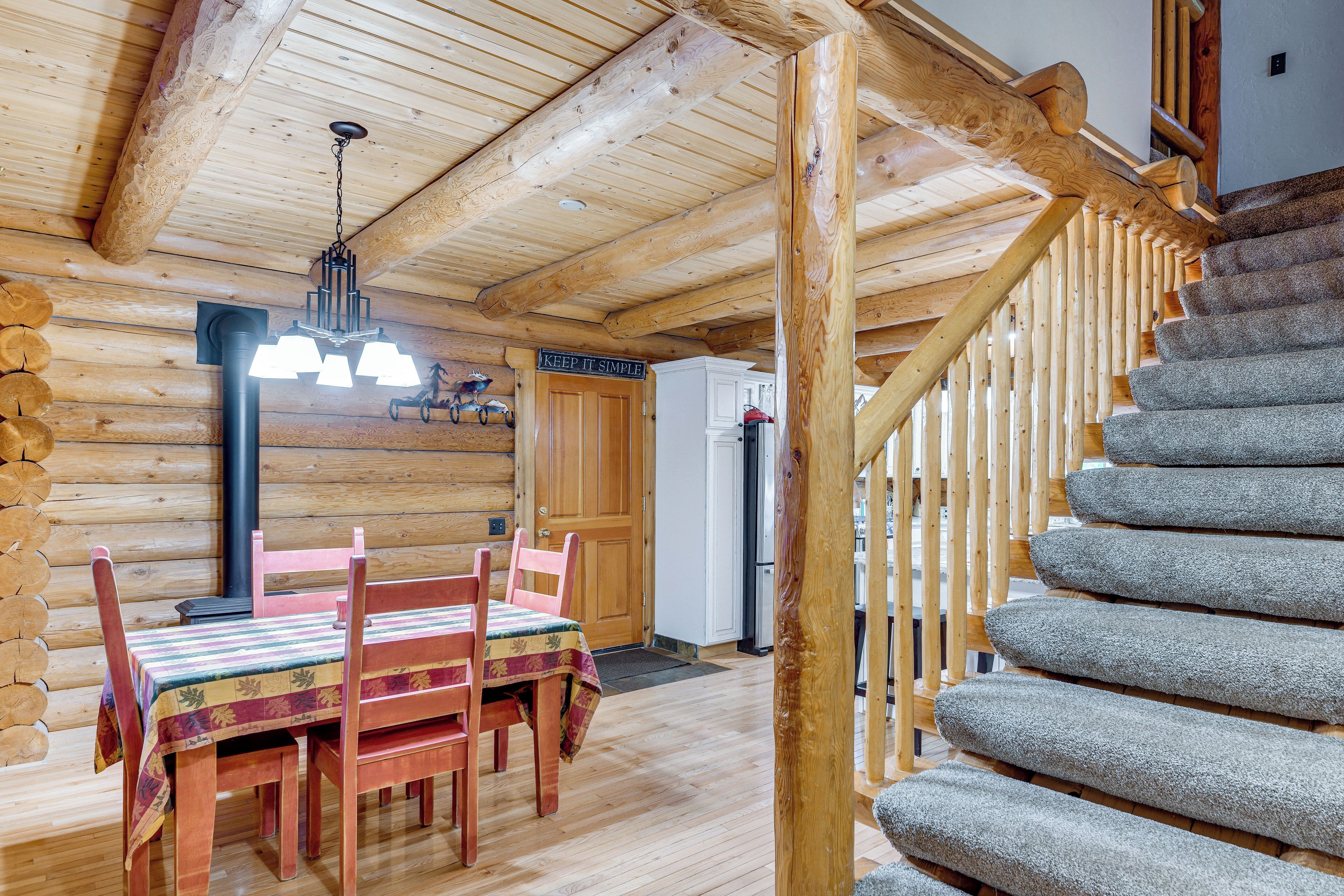 Un intérieur en bois comprenant une table et des chaises, un escalier et un coin cuisine.