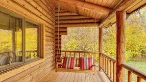 A wooden cabin with a porch, a swing, and a view of autumn foliage. - Along Big Wood River: Hailey Family Cabin w/ Yard (Hailey)