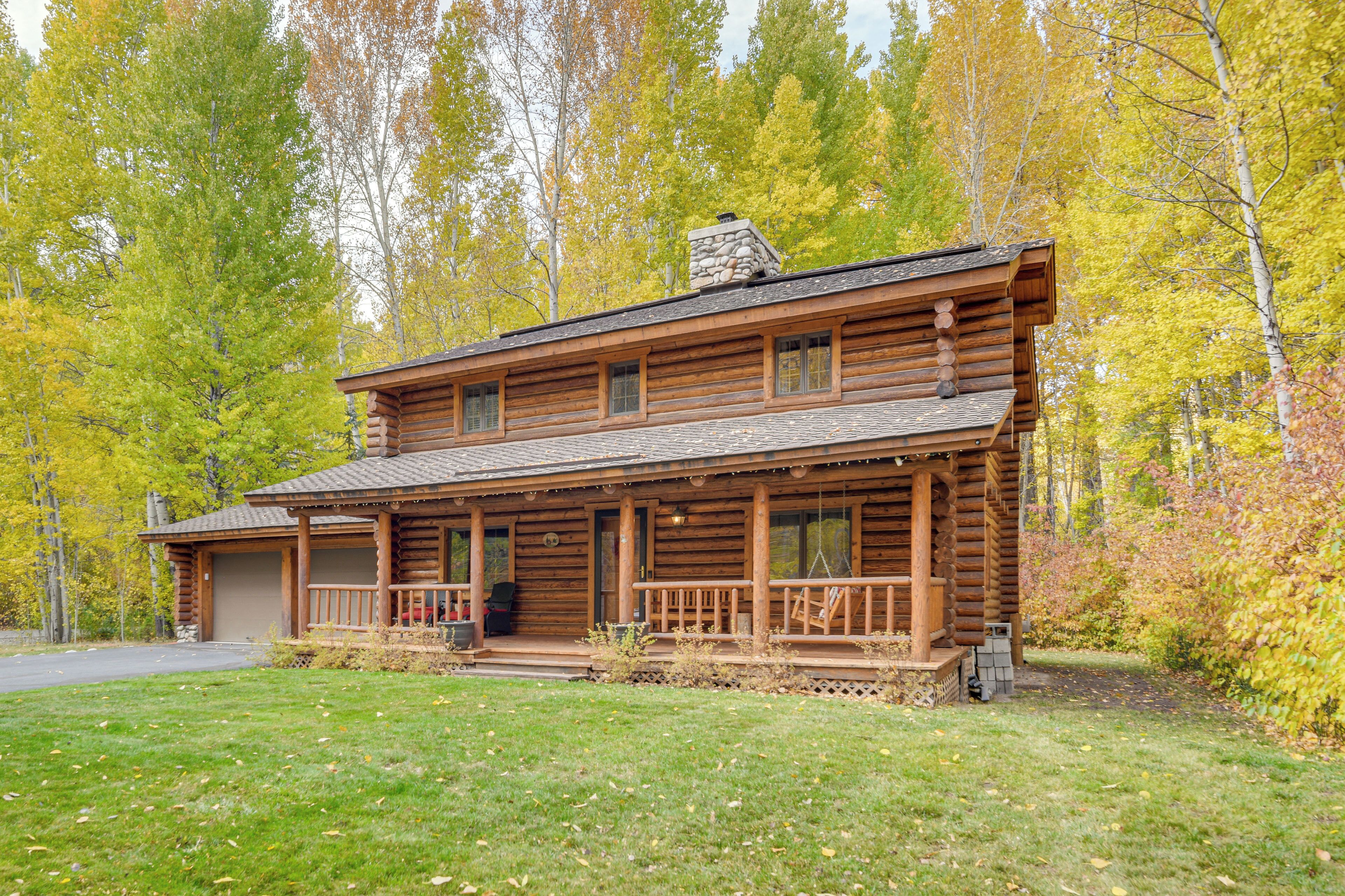 A log cabin with a porch, a chimney, and a garage.