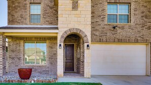 A two-story house with a brick facade, a large arched entryway, and a garage. - Close to Energy Giants! 3,300-sq-ft Midland Home (Midland)