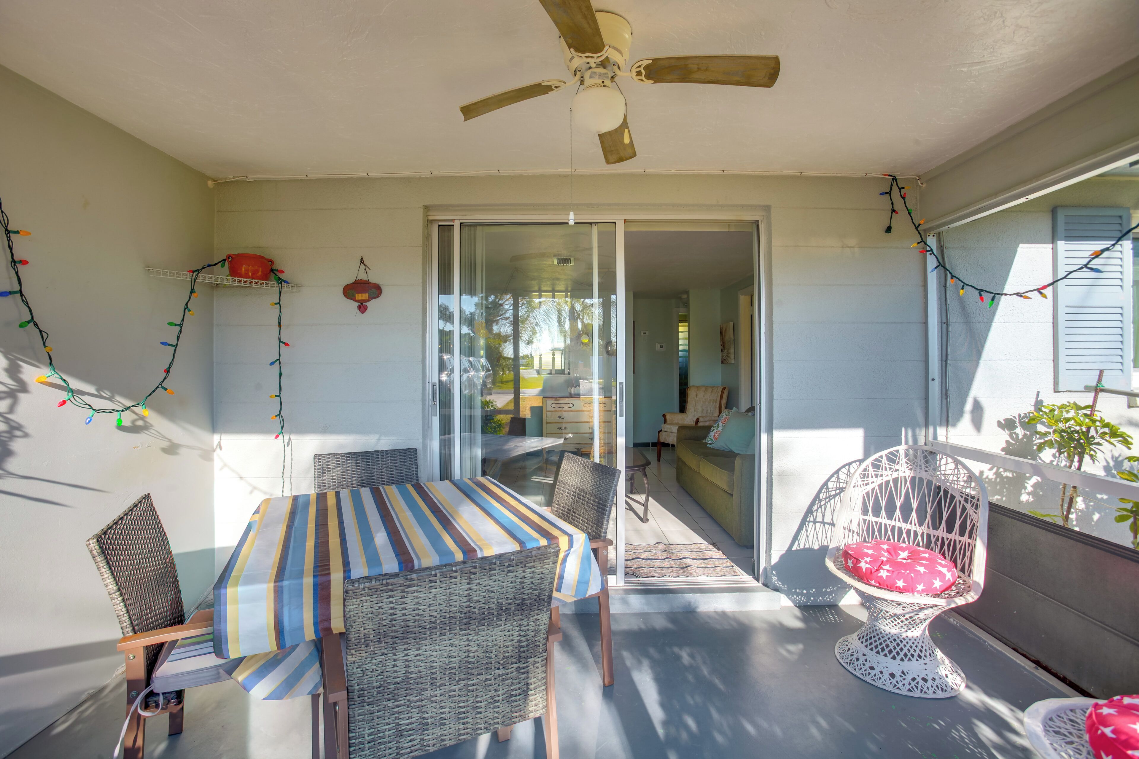 A covered patio with a dining table, chairs, and a ceiling fan.