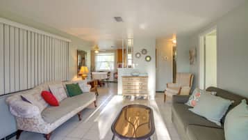 A spacious living room with a sofa, a coffee table, and a dining area in the background.