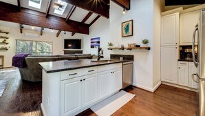 A modern kitchen with white cabinets, a large island, and a built-in refrigerator.