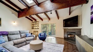 A living room with a sectional sofa, ottoman, and a fireplace.