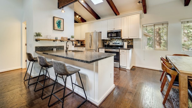 A spacious kitchen with a central island, white cabinetry, and a wooden ceiling.