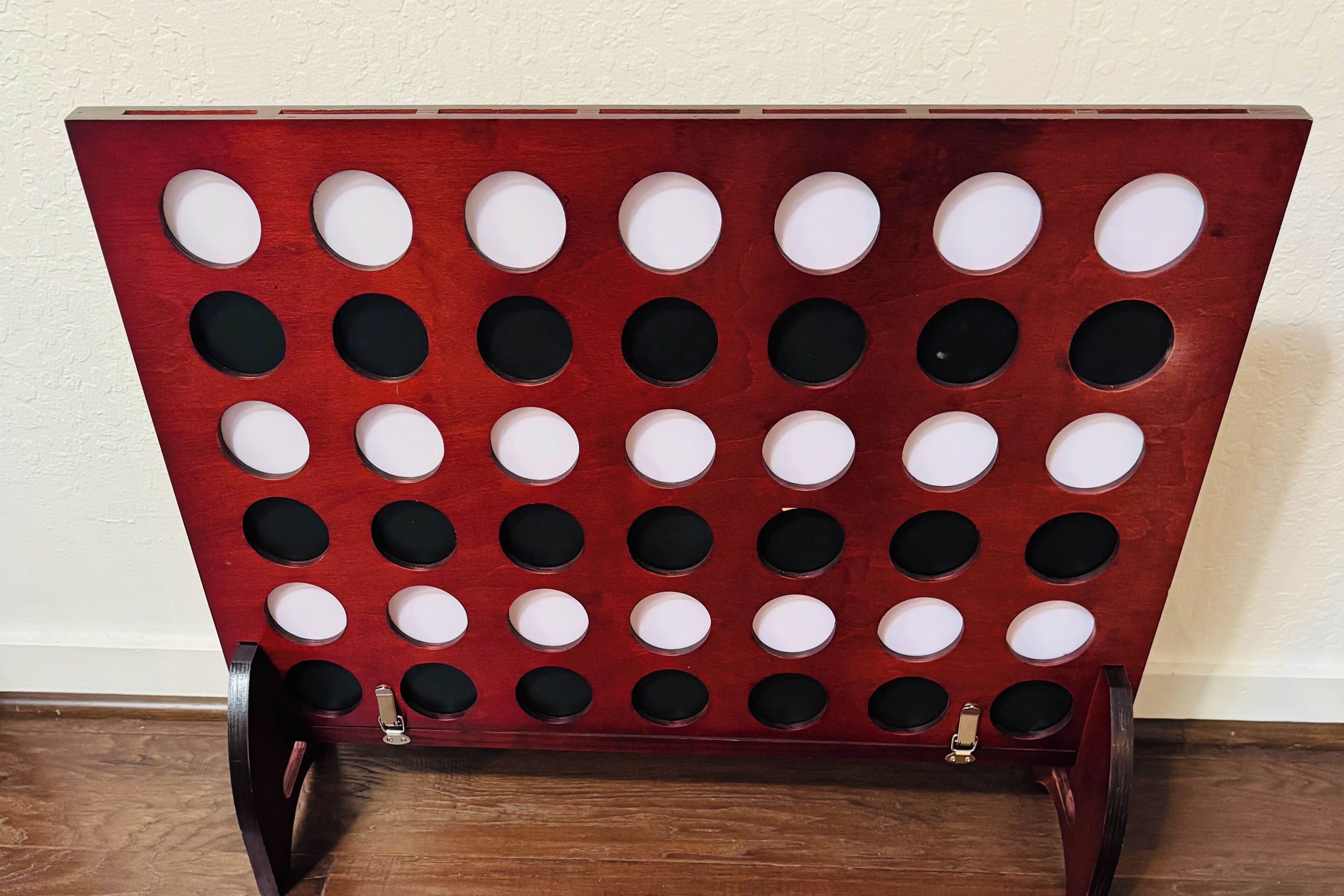 A wooden board with circular cutouts arranged in a grid pattern, supported by metal legs.