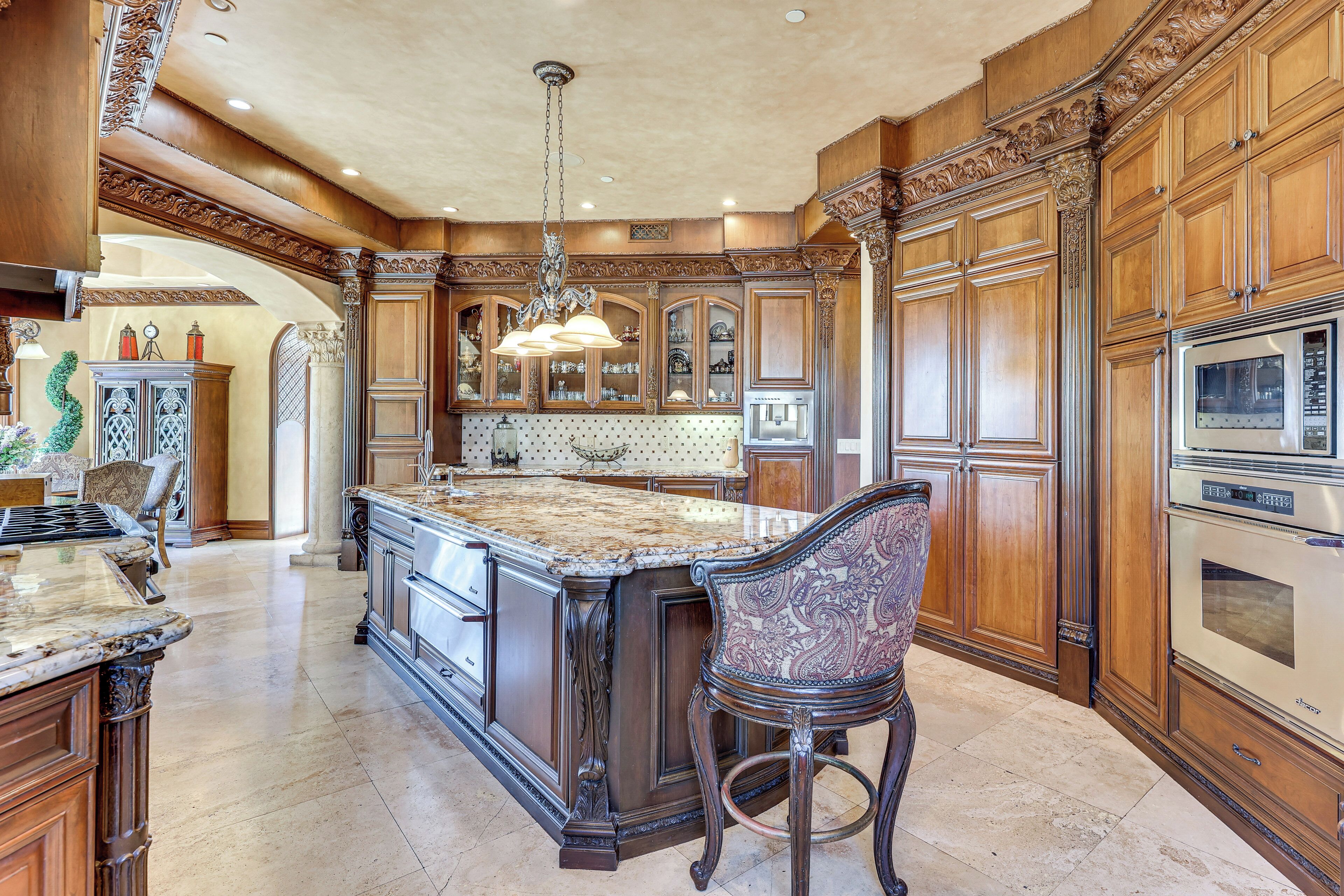 A spacious kitchen with a large island, wooden cabinetry, and modern appliances.