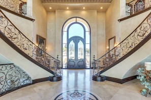 A grand entrance with two ornate staircases, a large arched doorway, and a polished marble floor. - Grand 9,000-sq-ft Estate! Luxurious Socal Getaway (La Mesa)