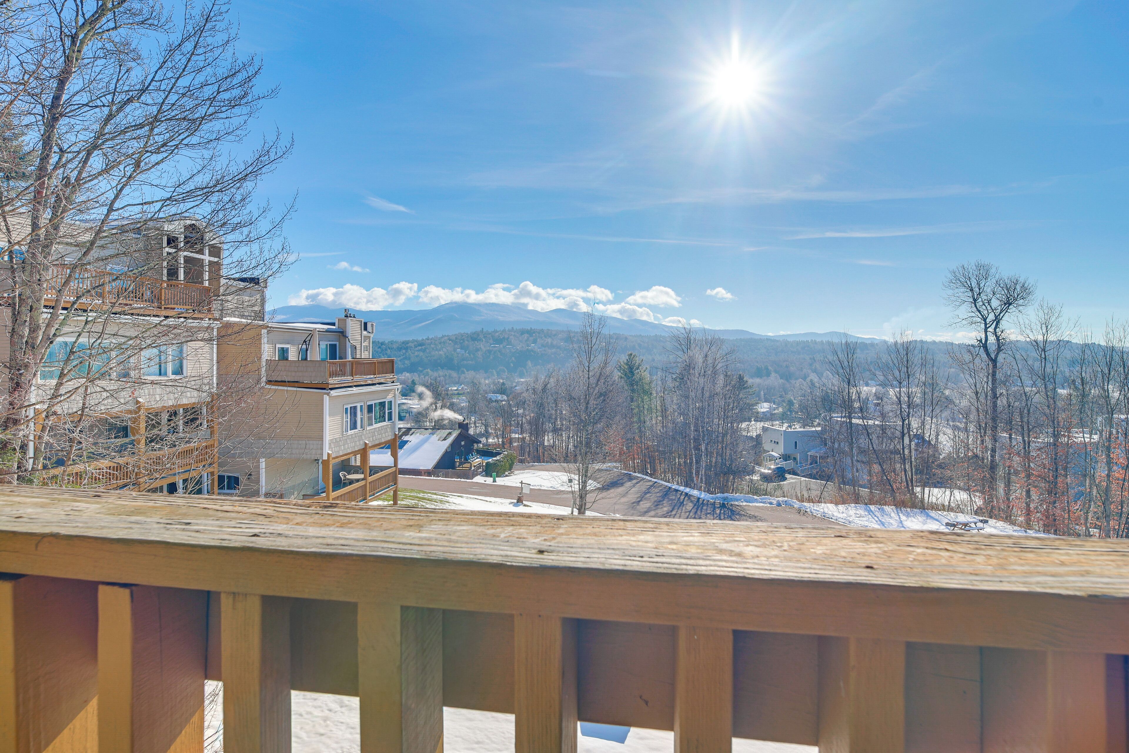 Zona residencial con terraza de madera, casas y una cadena montañosa al fondo.
