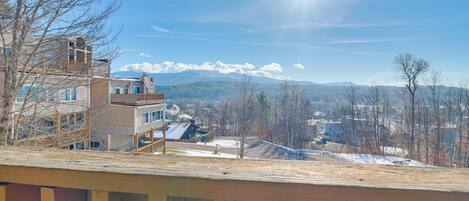 Zona residencial con terraza de madera, casas y una cadena montañosa al fondo.