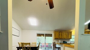 Una cuina àmplia amb armaris de fusta, una zona de dinar amb taula i cadires, i un ventilador de sostre.