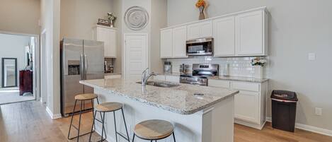 A modern kitchen with white cabinetry, stainless steel appliances, and a granite countertop.