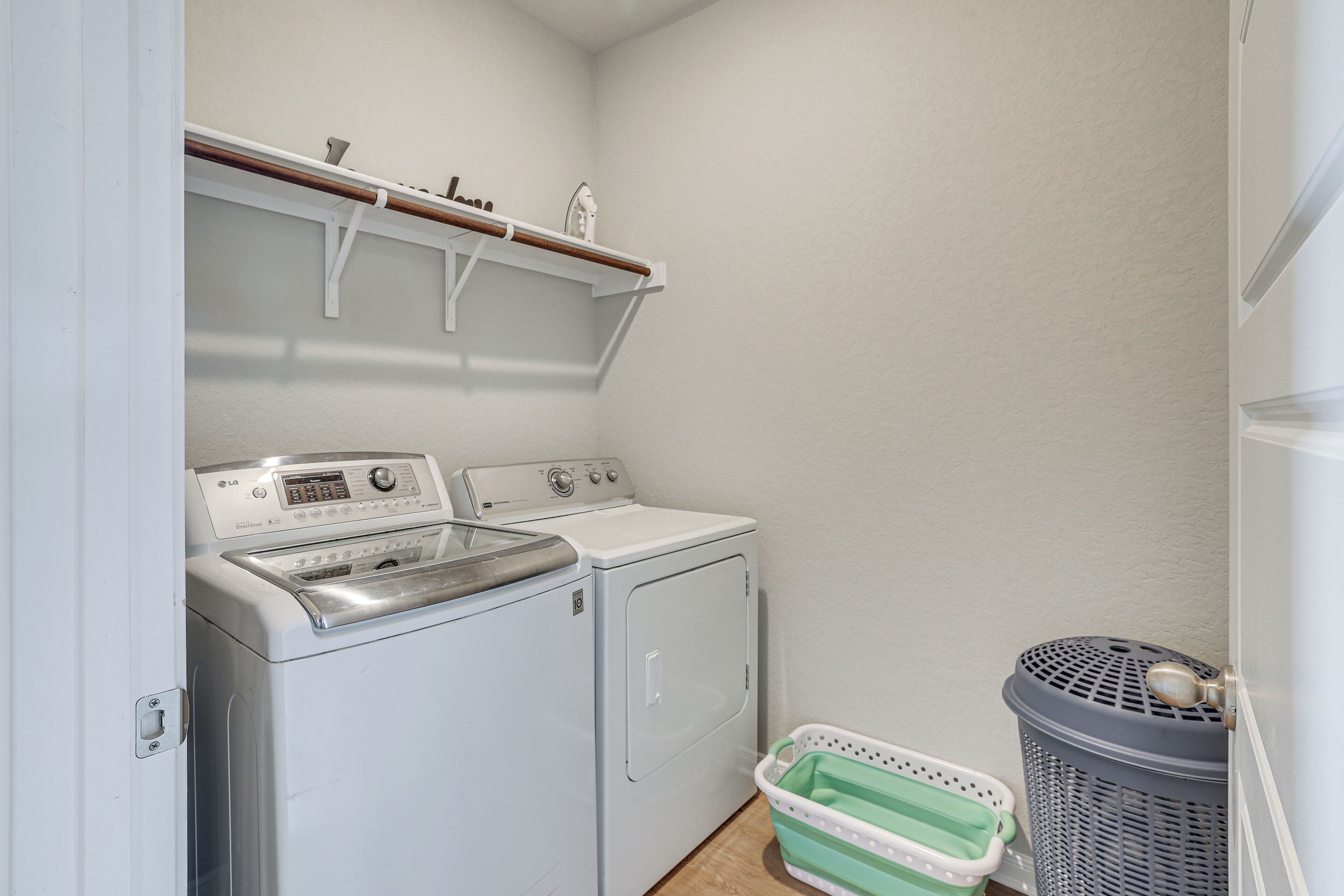 A laundry room with a washing machine, dryer, and a basket.