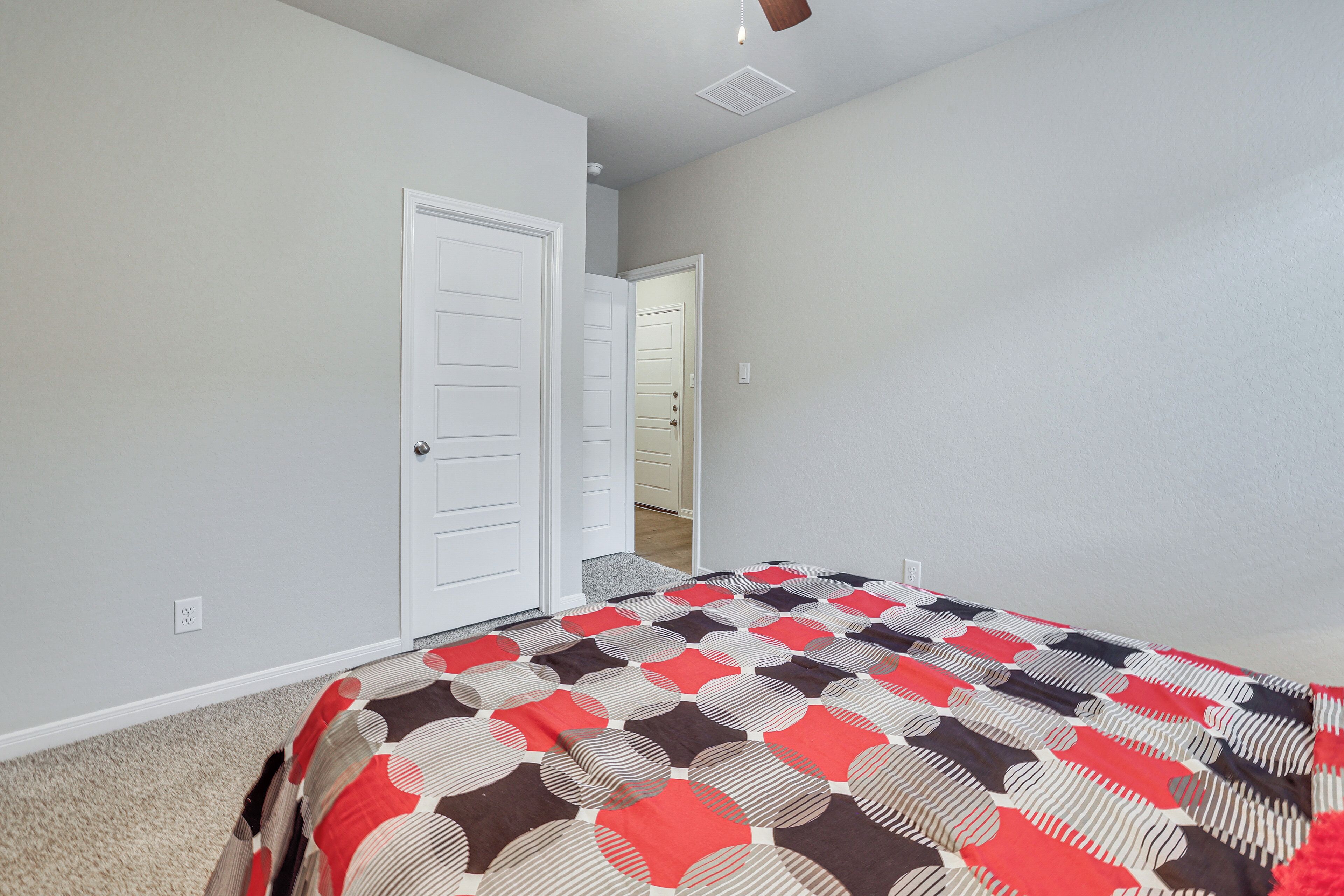Quarto com cama, porta e corredor que dá para outro cômodo.