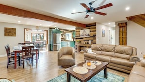 A spacious living room with a wooden dining table, leather sofa, and a ceiling fan. - Game Room & Resort Perks! Split Rock Retreat (Lake Harmony)