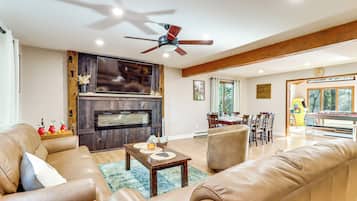 A spacious living room with leather sofas, a wooden coffee table, and a fireplace.