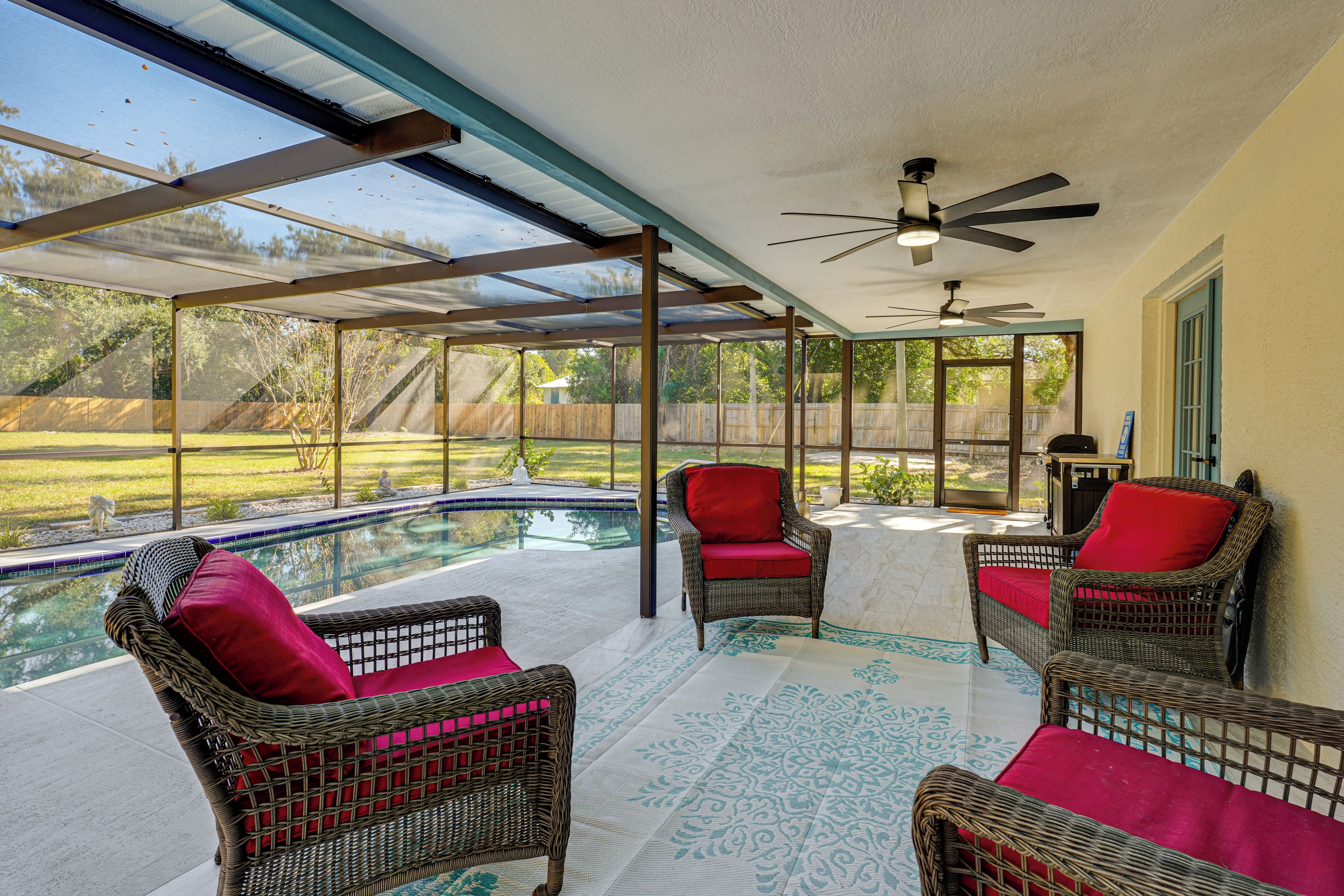 A covered patio area with wicker furniture and a pool.