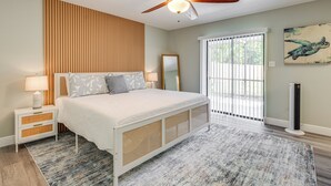 A bedroom with a bed, nightstand, ceiling fan, and a view of the outdoors through a window. - Modern Coastal Escape 1 Mi to Anclote River Park (Holiday)