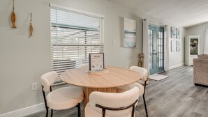 A dining area with a round wooden table, four chairs, and a welcome sign. - Modern Coastal Escape 1 Mi to Anclote River Park (Holiday)
