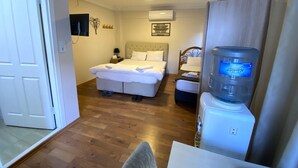 A hotel room with a bed, a smaller bed, a water dispenser, a desk, and a chair. - Meydan Pansiyon (İstanbul)