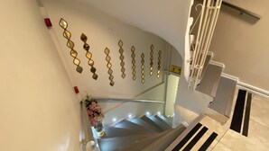 A staircase with a handrail, a wall-mounted decorative mirror, and a vase with flowers. - Meydan Pansiyon (İstanbul)
