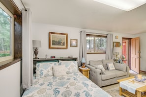 A bedroom with a bed, a sofa, a table, and a window with curtains. - Cute Hoodsport Cottage Close to Lake Kokanee! (Hoodsport)