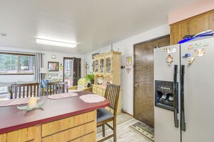Una cocina con una mesa de comedor de madera, sillas, un refrigerador y un armario.