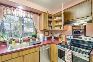 Una cocina con armarios de madera, un lavamanos de acero inoxidable, un lavavajillas, un horno y un microondas.