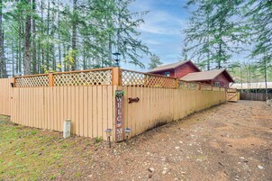 A wooden fence with a 'Welcome' sign, a red building, and a gravel driveway.