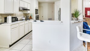 A kitchen with white cabinets, a countertop with appliances, and a door leading to another room. - Extended Stay in Sugar Land! Family Home w/ Yard (Sugar Land)