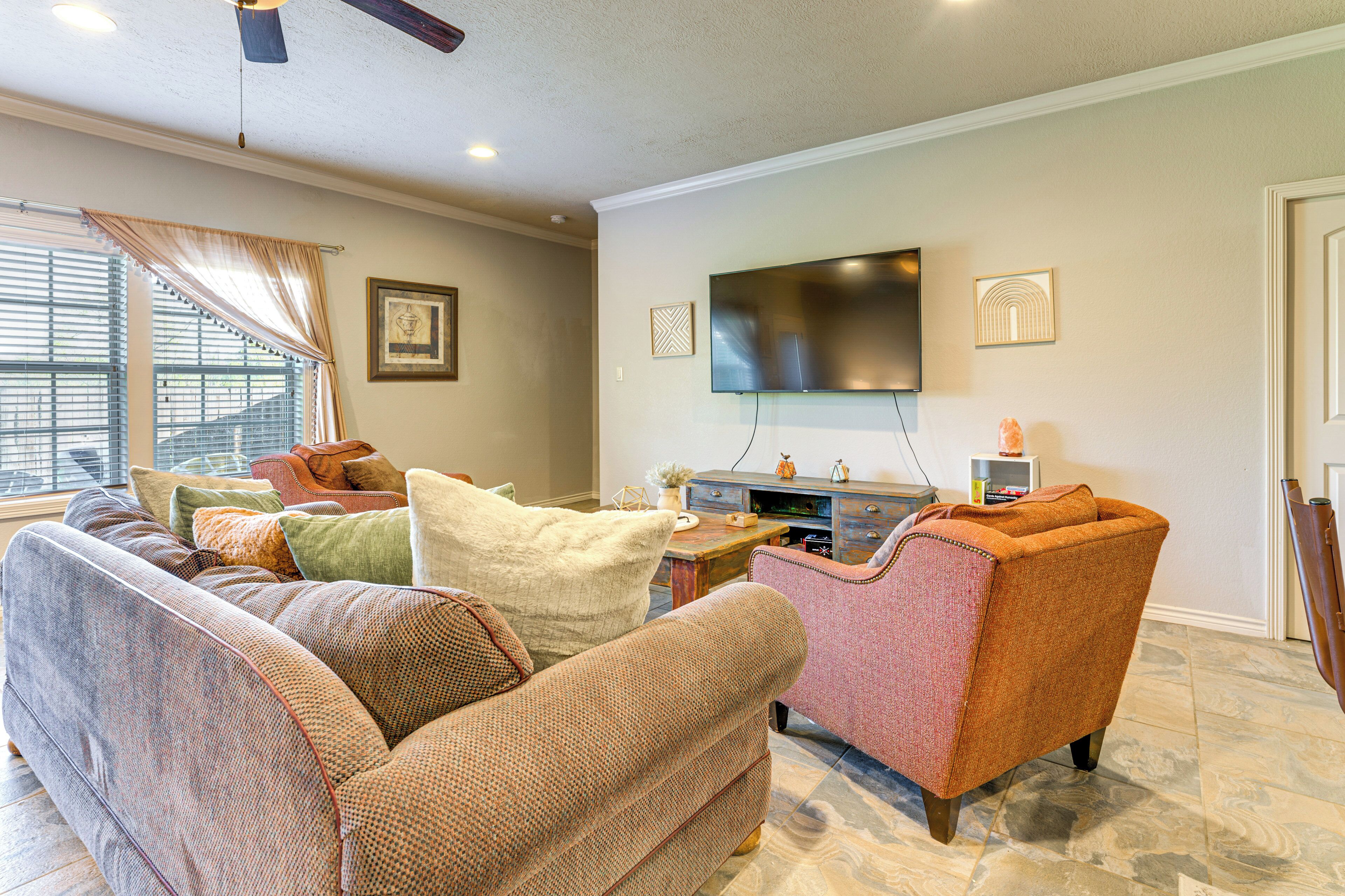 A living room with a sofa, armchair, and a flat-screen TV mounted on the wall.