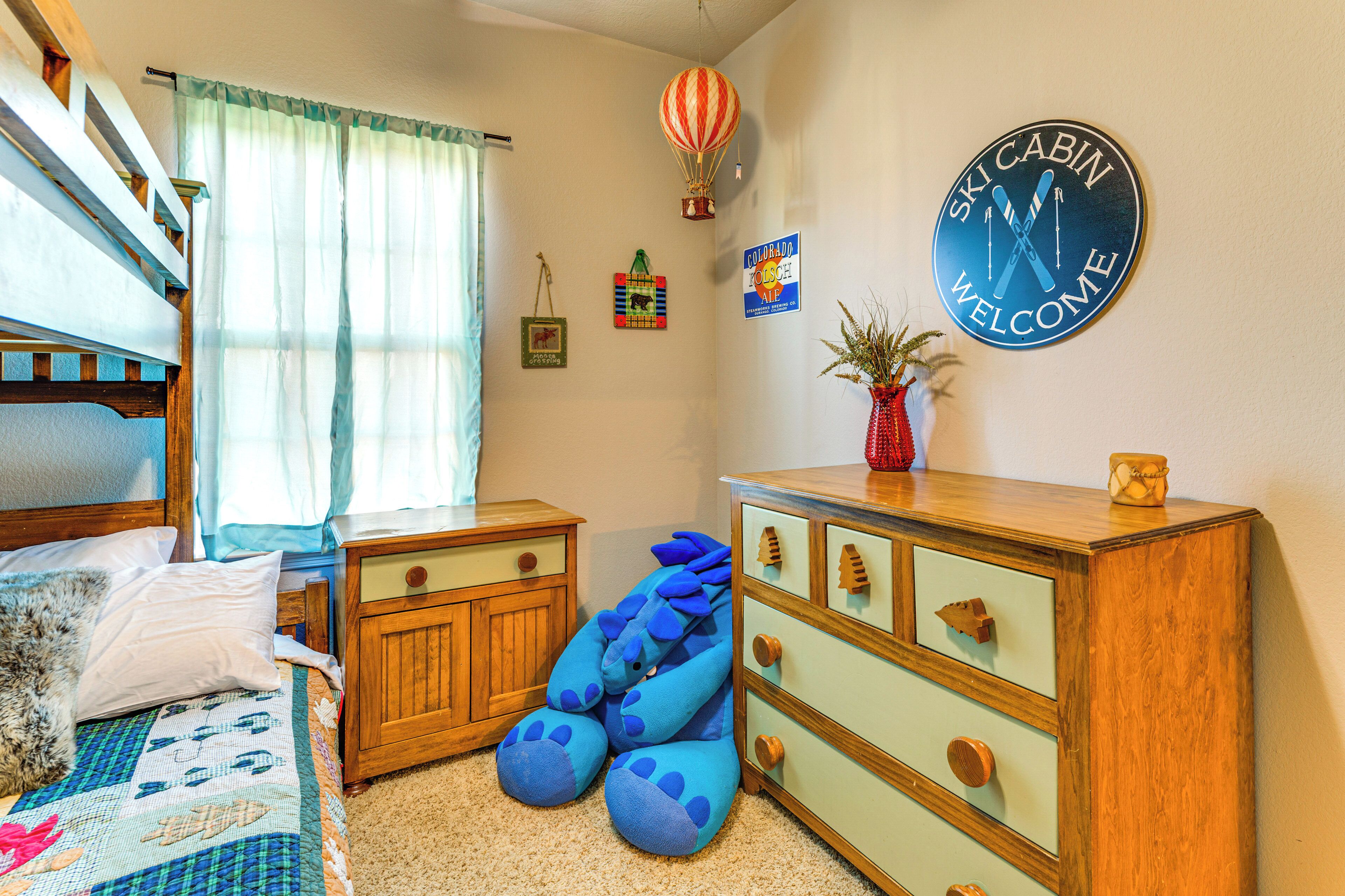 Un dormitorio con una cama individual doble, un aparador, un reloj de pared y un ventanal con cortinas.