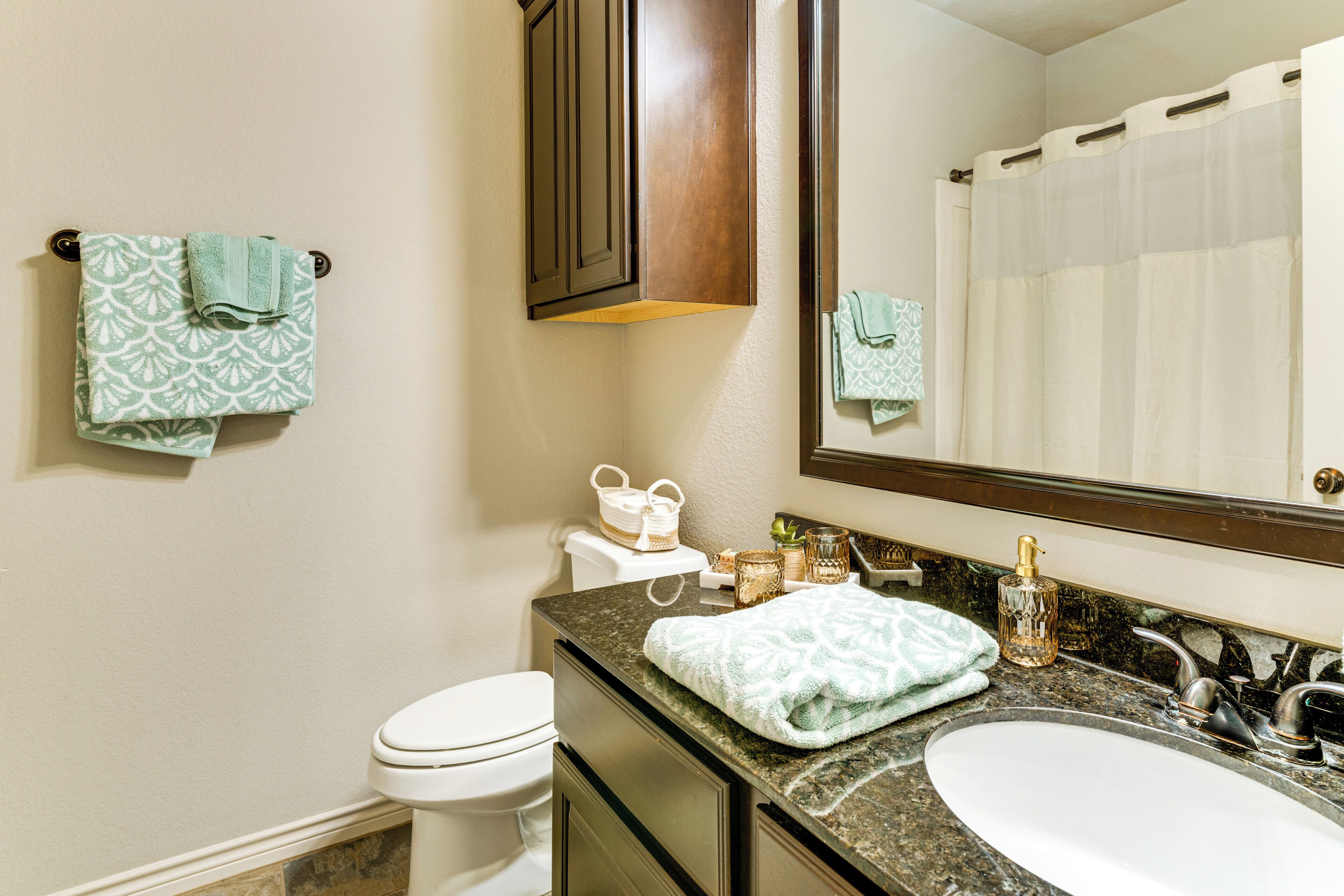 A bathroom with a white toilet, a sink with a mirror above it, and two towels hanging on hooks.
