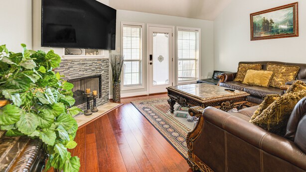 A living room with a fireplace, a leather sofa, a coffee table, and a flat-screen TV mounted on the wall. - Gateway to Aggieland! College Station Family Home (College Station)