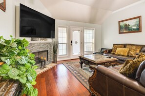 Un salon avec une cheminée, un canapé en cuir, une table basse et un téléviseur à écran plat fixé au mur.