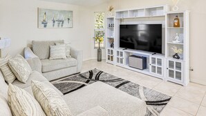 A living room with a grey sofa, a flat-screen TV, and a white entertainment unit. - Canal-front Home w/ Fishing Dock in Port Charlotte (Port Charlotte)