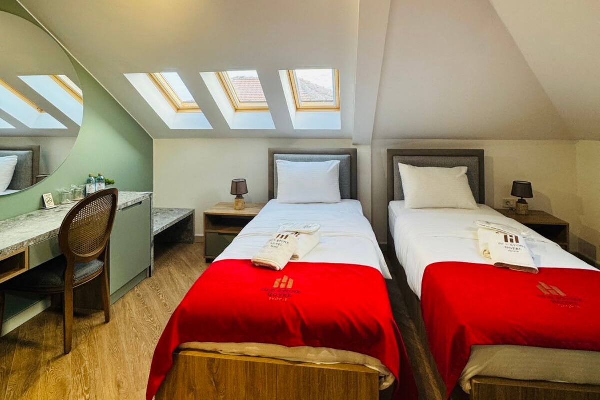 Ein Hotelzimmer mit zwei Betten, einem Schreibtisch und Dachfenstern.