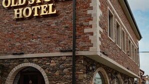 The exterior of the Old Stone Hotel with a prominent sign, stone and brick facade, and arched windows. - Old Stone Hotel Skopje (Skopje)