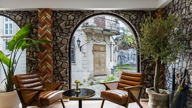 A cozy indoor seating area with leather chairs, a small round table, and a potted plant. - Old Stone Hotel Skopje (Skopje)