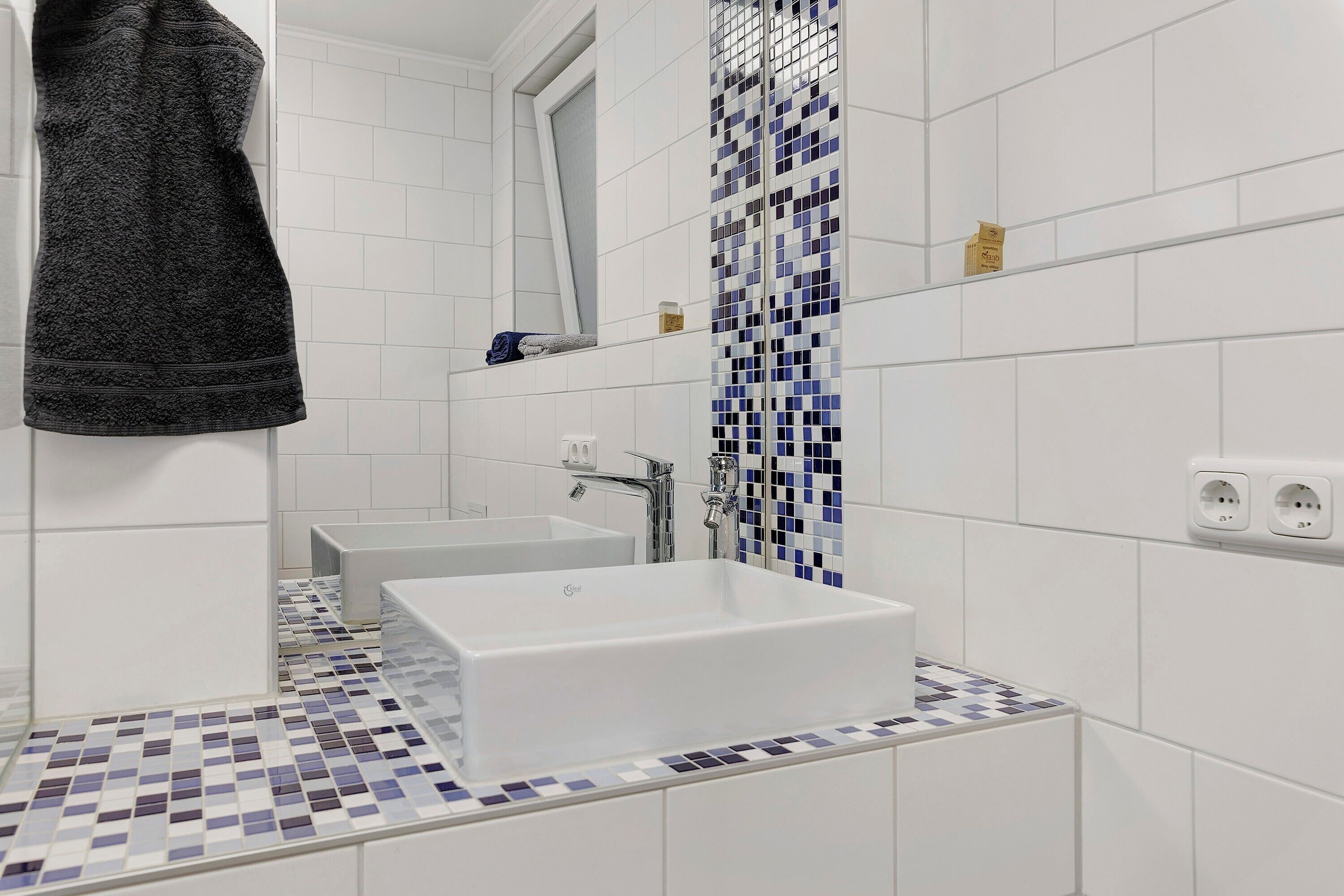 Ein Badezimmer mit einem weißen Waschbecken, einem Spiegel und Fliesenboden.