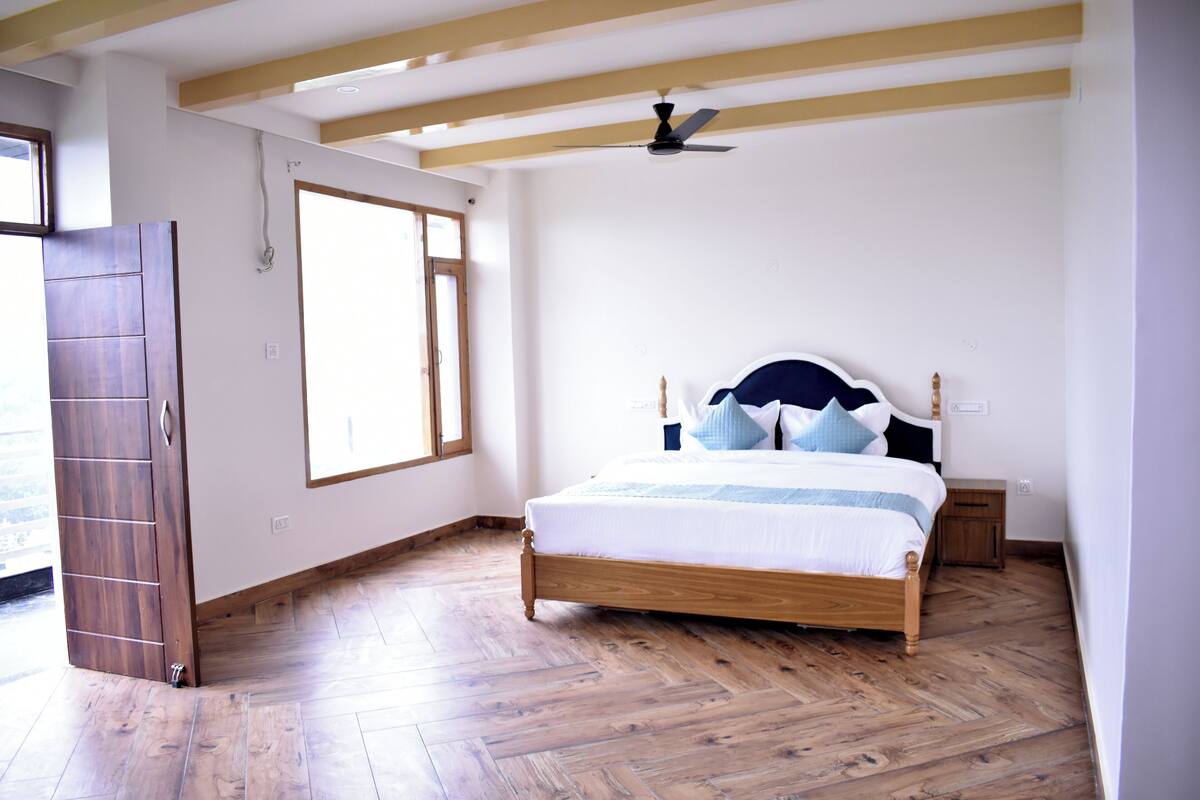 A bedroom with a wooden bed, a ceiling fan, and a large window.